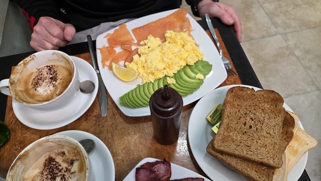 Two people at a table with scrambled eggs, smoked salmon, avocado and toast