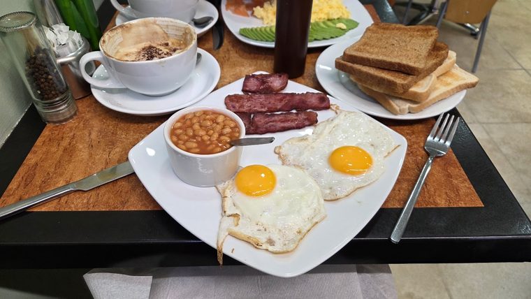 Fried eggs, sausages, beans and toast with a mug of tea