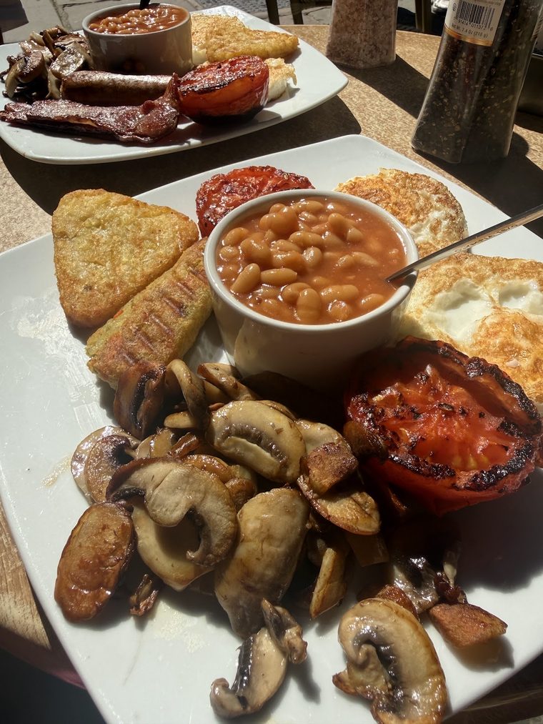 A full English breakfast across two plates with hash browns and toast